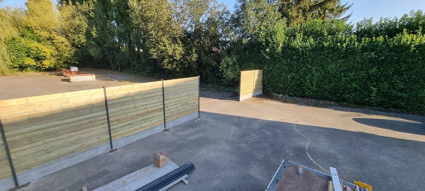 a99e3d9ea15f4377883259950164ad02 Clôture bois claire posée le long d'une cour goudronnée avec haie verte et arbres