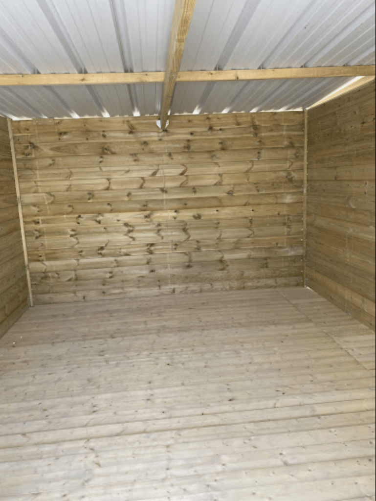 Intérieur d'abri de jardin en bois avec parois en clins, plancher bois et toiture bac acier