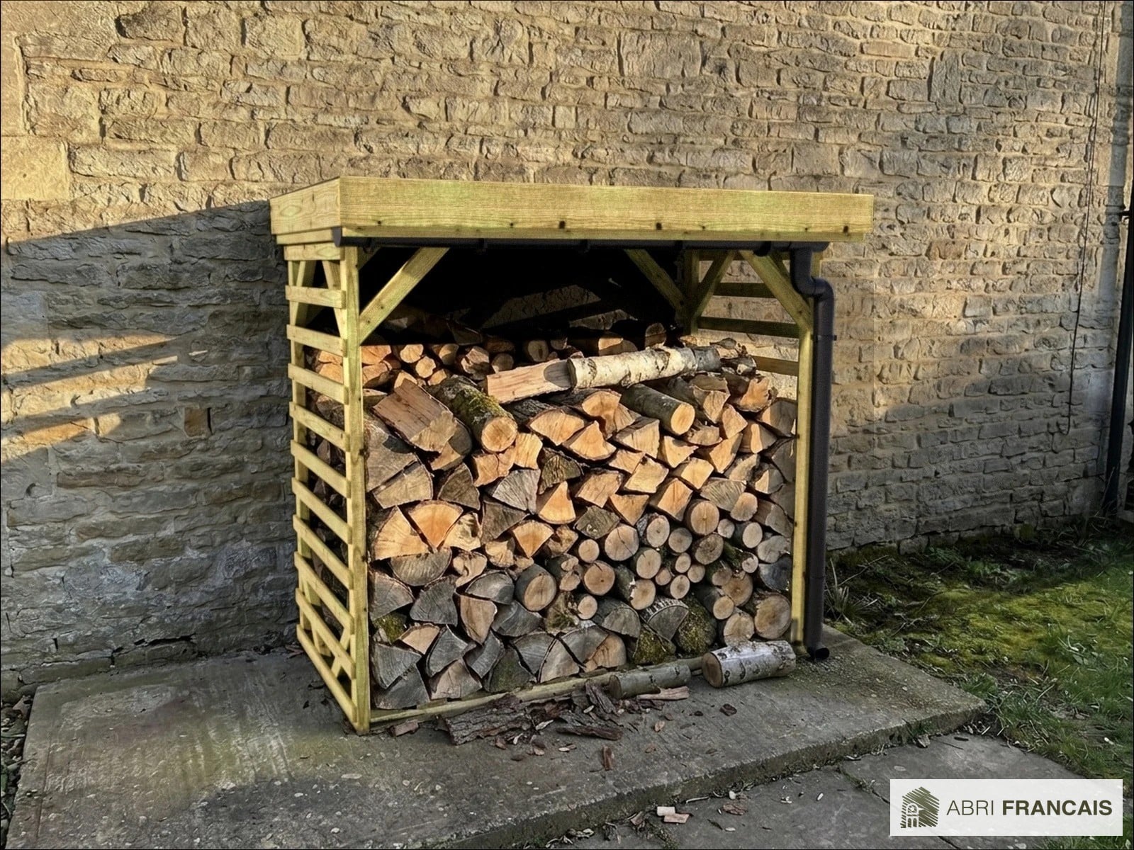 Abri à bûches 2 m × 1,30 m, adossé, avec gouttière – mise en situation